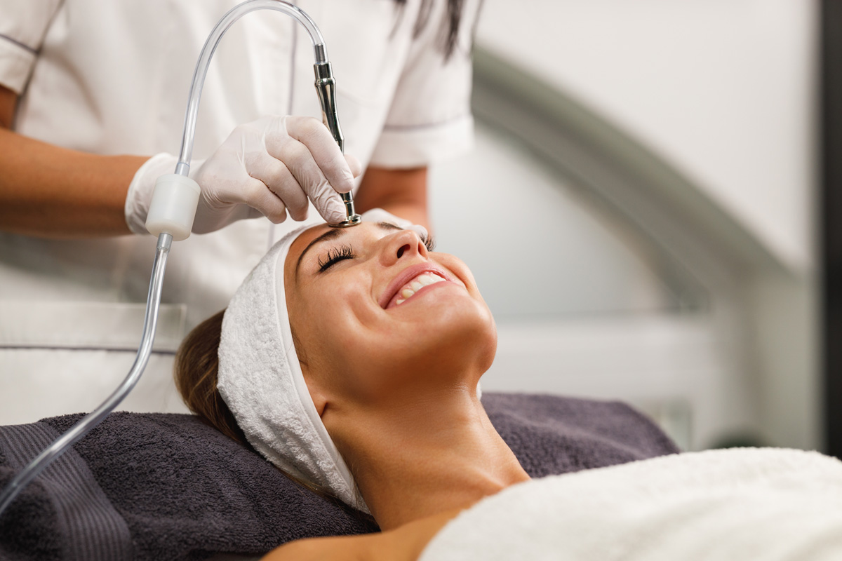 A smiling woman receiving a microdermabrasion treatment at a Richmond med spa.